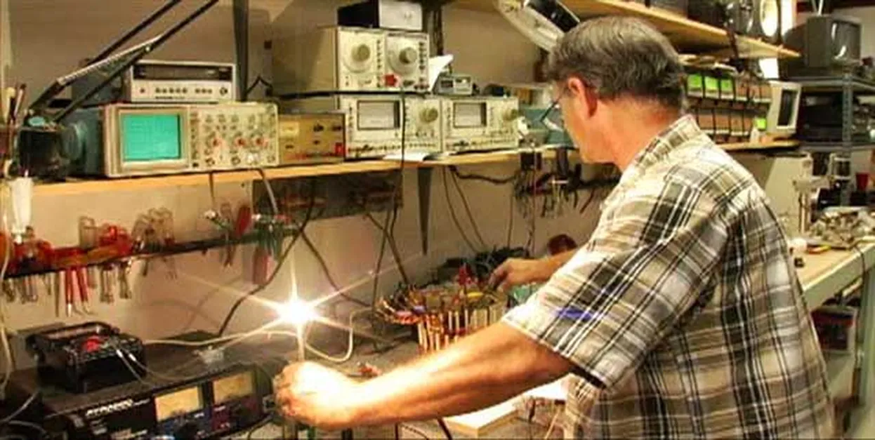 A technician working on electronic devices in a workshop filled with instruments and tools